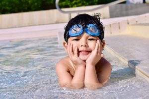 Schwimmen lernen: Kind mit Taucherbrille im flachen Wasser