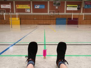 Federfußball: zwei Füße und ein Ball auf Sporthallenboden