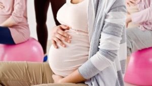 Fitness in der Schwangerschaft: schwangere Frau hält Bauch auf Sitzball