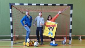 Mitarbeitende des Kinderbüros in Fußballtor mit Halli Galli Plakat