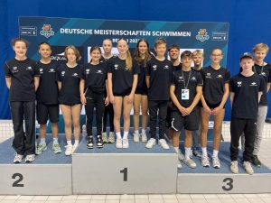 Gruppenbild auf dem Siegertreppchen: Die Athletinnen und Athleten der SGS Münster