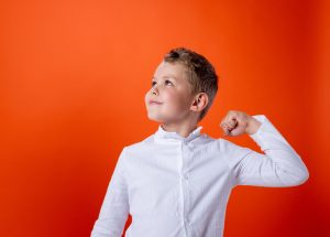 Symbolbild Mut tut gut: Junge vor orangener Wand